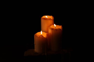 Siyah arka planda dans eden üç mum yanıyor. 