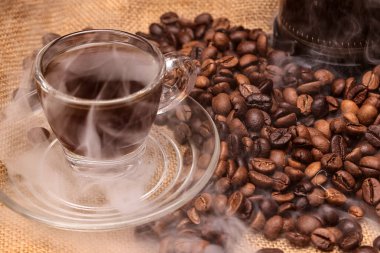 Koyu kahverengi kahve, kahve, makro yakın çekim akışı, düşüş, çömlek, sigara içme, şeffaf cam fincan tabağı, jute kumaş arka planına sıvı dökme. 