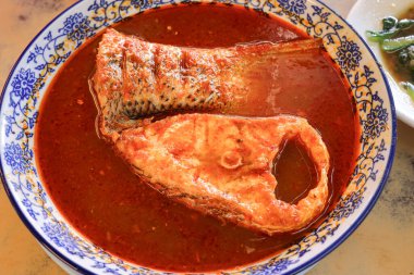 Malezya Peranakan baharatlı balık ikan asam pdas kırmızı soslu levrek yol kenarındaki restoranda. 