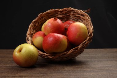 Yeşil sarı kırmızı olgun armut tatlı sulu sepet içinde ahşap masa üzerinde koyu arkaplan