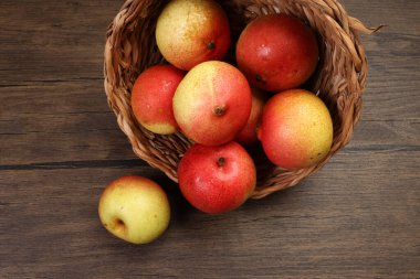 Yeşil sarı kırmızı olgun armut tatlı sulu sepet içinde ahşap masa üzerinde koyu arkaplan