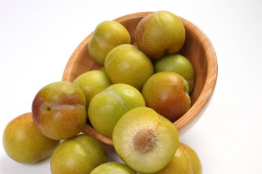 Olgun, küçük, tatlı erik yeşil kestane rengi beyaz arka planda 