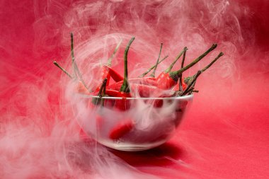 Kırmızı dumanlı kuşların gözü kırmızı arka plan buharında cam kasede kırmızı biber. 