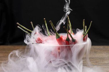 Dumanlı kırmızı kuşlar göz kırmızı biber siyah arka plan buhar buharında cam kase içinde 