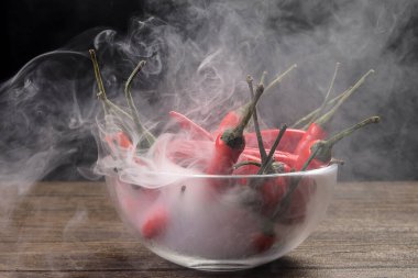 Dumanlı kırmızı kuşlar göz kırmızı biber siyah arka plan buhar buharında cam kase içinde 