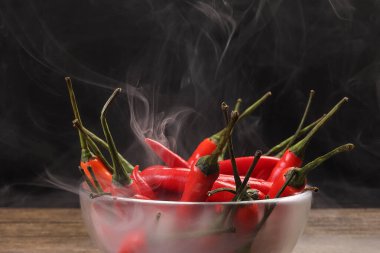Dumanlı kırmızı kuşlar göz kırmızı biber siyah arka plan buhar buharında cam kase içinde 