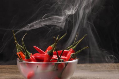 Dumanlı kırmızı kuşlar göz kırmızı biber siyah arka plan buhar buharında cam kase içinde 