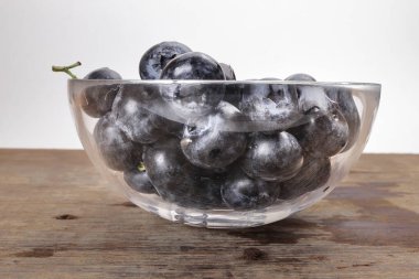 Taze olgun yabanmersinleri ahşap arka planda cam kasede ahşap mavi böğürtlen 