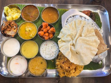 Hintli vejetaryen thali, on dokuz çeşit sebze ürünüyle tatlı, tuzlu, tuzlu, umami baharatlı pirinç chapati biryani, baharatlı, papatya soslu, paslanmaz çelik tepsi. 