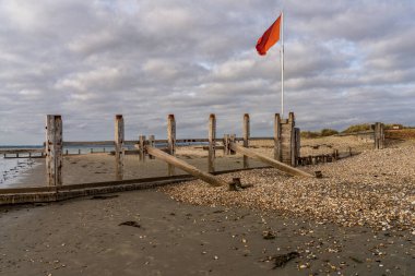 Batı Wittering, Batı Sussex, İngiltere, İngiltere sahillerinde kara bulutlar ve kırmızı bayrak