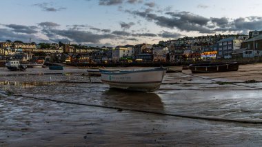 St Ives, Cornwall, İngiltere, İngiltere - 30 Mayıs 2022: Akşamları kara bulutlar ve alçak gelgitte limandaki tekneler