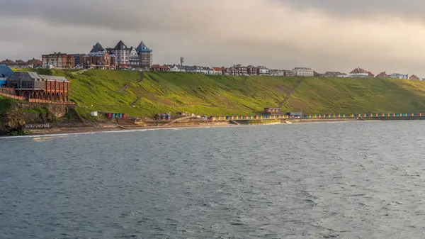 stock image Whitby, North Yorkshire, England, UK - June 20, 2023: View of the West Cliff and the Beach Huts at high tide