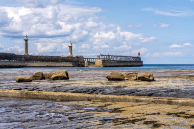 Whitby, Kuzey Yorkshire, İngiltere - 21 Haziran 2023: Doğu Kayalıkları 'ndaki Kuzey Denizi kıyısından deniz fenerlerine doğru görüş
