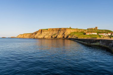 Whitby, Kuzey Yorkshire, İngiltere - 21 Haziran 2023 Doğu Kayalıkları ve St. Mary Kilisesi 'ndeki evler üzerinde altın saat