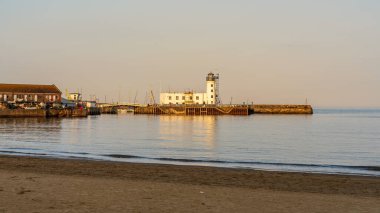 Scarborough, North Yorkshire, England, UK - June 22: 2023: Scarborough Lighthouse in the evening light, seen from South Bay Beach clipart