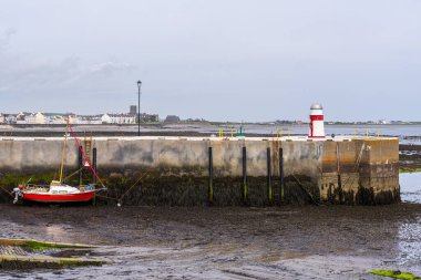 Castletown, Rushen, Isle of Man - May 18, 2023: The small lighthouse and a boat on the pier clipart