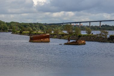 Clyde Nehri kıyısında Bowling, Batı Dunbartonshire, İskoçya 'da, Arkaplanda Erskine Köprüsü olan bir gemi enkazı