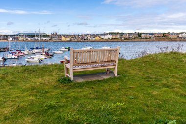 Elie Beach, Fife, Scotland, UK - September 14, 2023: A bench with a view of the houses on the promenade clipart