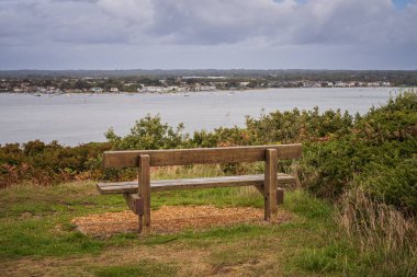 A bench overlooking Christchurch habour in Hengistbury Head, Dorset, England, UK clipart