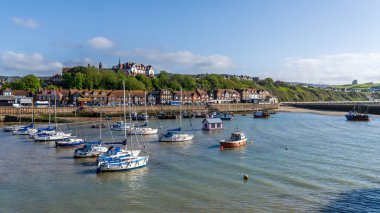 Folkestone, Kent, England - May 08, 2022: Boats at low tide in the harbour and the houses on the shore clipart