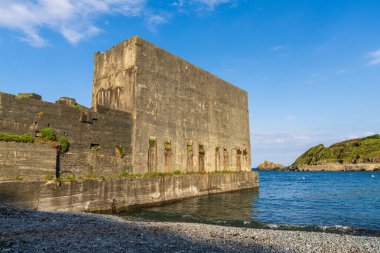 Porthoustock, Cornwall, England, UK - June 03, 2022: Porthoustock Beach and the disused concrete Silo clipart