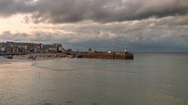 St Ives, Cornwall, İngiltere, İngiltere - 30 Mayıs 2022: Akşamları kara bulutlar ve alçak gelgitte limandaki tekneler