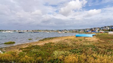 Mudeford Sandbank, Dorset, İngiltere - 27 Eylül 2022: Webb Körfezi 'ndeki sahil kulübelerinin ve teknelerin görüntüsü