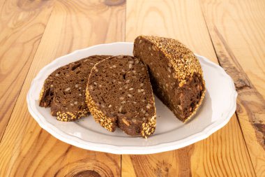 Tahta bir masada seramik beyaz tabakla üç parça çavdar ekmeği, makro..