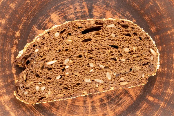 Jeden Kus Žitného Multigrainového Chleba Hliněné Desce Makro Horní Pohled — Stock fotografie