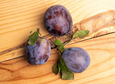 Üç organik siyah erik, yakın plan, ahşap bir masanın üstünde, en üstte..