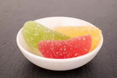 Üç tatlı marmelatlı şeker beyaz bir tabakta kayrak taşı üzerinde, makro.