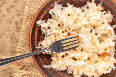 Lahana turşusu, kil tabakta metal çatal, jute bez, makro, üst manzara..