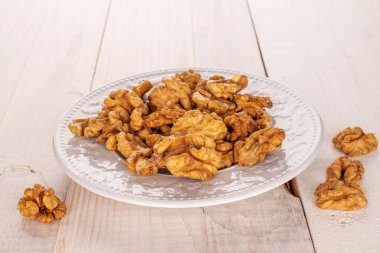 Ahşap bir masada beyaz seramik tabakta soyulmuş ceviz, makro..