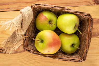 Tahta bir masada sepetin içinde birkaç tane yeşil elma, makro, üst manzara..