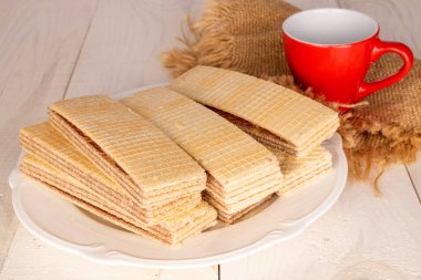 Beyaz tabağı ve kırmızı fincanı olan birkaç tane çikolatalı gofret..