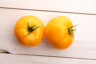 Üç taze organik, olgun sarı domates boyalı ahşap bir masa, üst manzara.