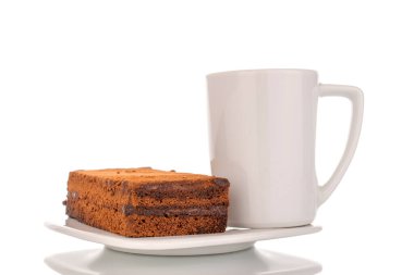 Seramik beyaz çay tabağı ve fincanda bir parça mantarlı kek, beyaz arka planda makro çekim.