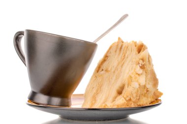 Seramik tabakta bir parça kremalı pasta ve siyah fincan, makro, beyaz arka planda izole edilmiş..