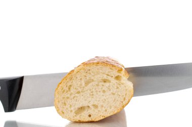 One half of fresh aromatic baguette with metal knife, macro, isolated on white background.