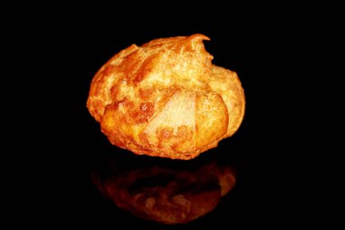 One delicious fresh Chouquettes, close-up, isolated on black.