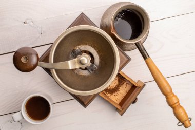 Manual coffee grinder on a white painted wooden table, top view.