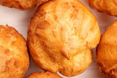 Several fresh fragrant chouquettes on a wooden table, close-up, top view.