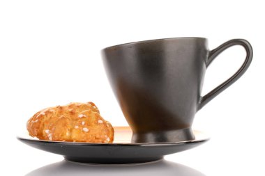 One sweet chouquette with a cup on a saucer, close-up, isolated on white.
