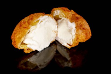 One fragrant cut in half Chouquettes, close-up, on a black background.