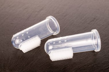 Two dog toothbrushes, close-up, on slate stone.