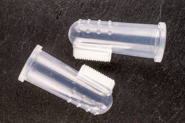 Two dog toothbrushes, macro, on slate stone, top view.