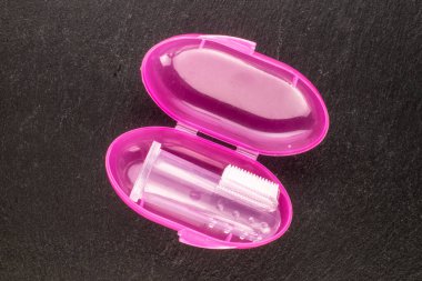 One dog toothbrush in plastic containers, macro, on slate stone, top view.