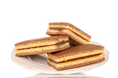 Three mini cocoa biscuits on a white ceramic saucer, macro, isolated on a white background.