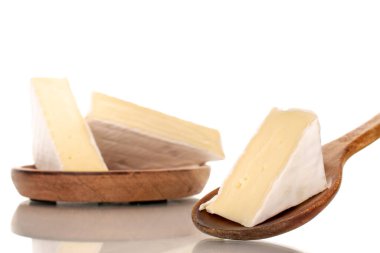 Three pieces of fragrant Brie cheese on a wooden plate with a wooden spoon, macro, isolated on a white background.
