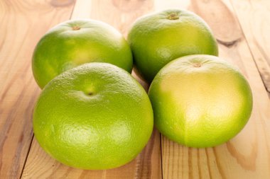 Several organic bright green Citrus Sweetie on a wooden table, close-up.